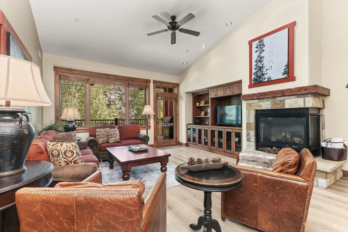 The hero image showcases a stylish penthouse living room with a plush sofa arranged around a stone fireplace, large windows framing mountain views, and a cozy atmosphere perfect for relaxing or gathering with friends and family.