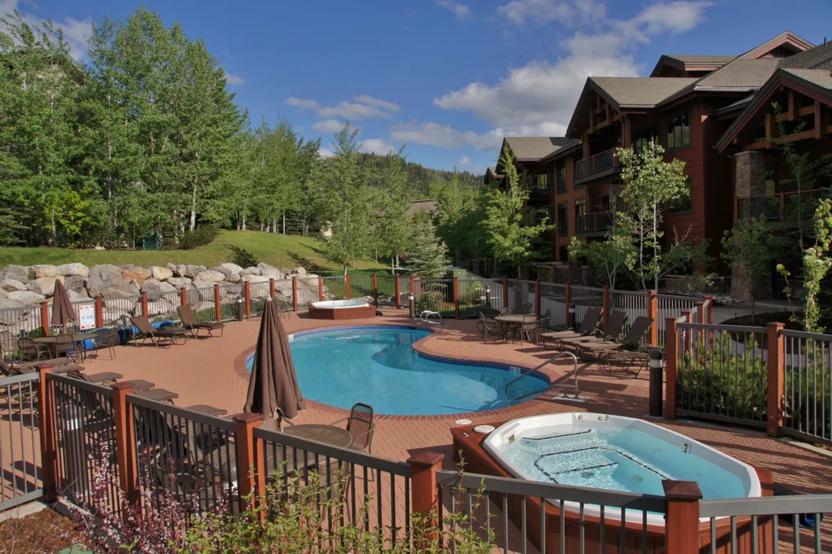 A relaxed outdoor pool and hot tub area surrounded by lush greenery and lounge chairs, ideal for swimming, sunbathing, or unwinding after a day’s adventure. The scene transitions easily from daytime relaxation to evening gatherings.